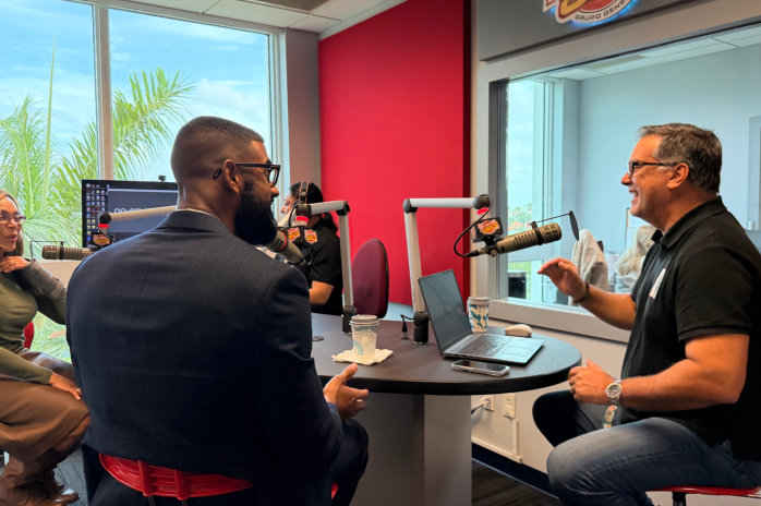 two men having a conversation in a studio with microphones on a table