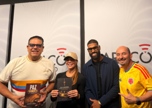 four people posing together, two of them holding books