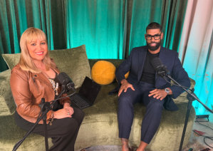 a woman and a man sitting on a green couch with microphones in front of them