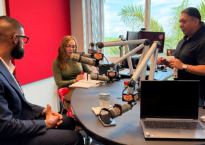 a group of people gathered around a table with microphones in a radio studio